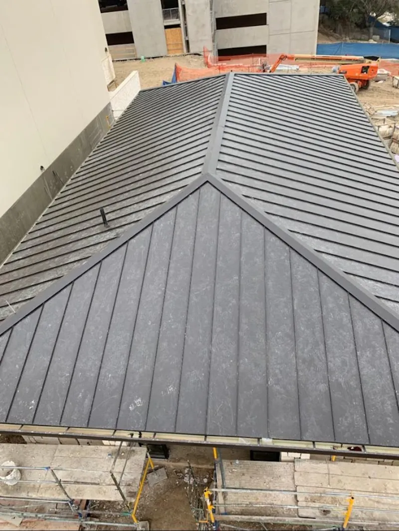 Commercial metal roof construction with crane equipment in Groton